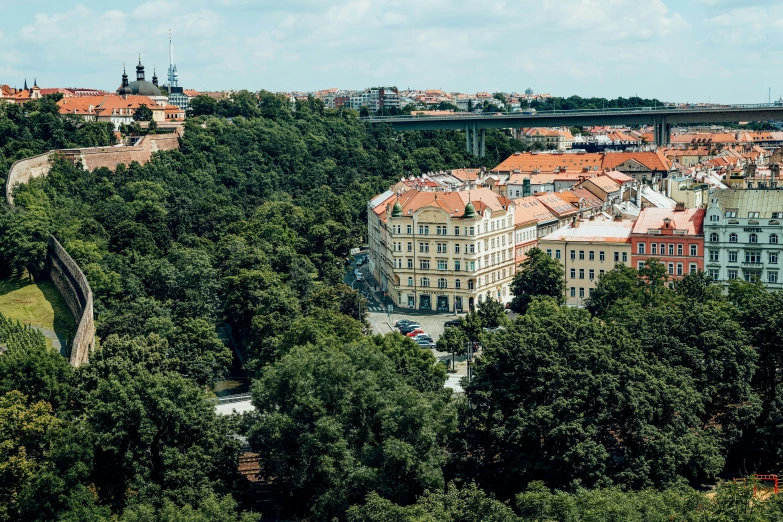 a view of a city from the top of a hill, danube school, prague in the background, square, lush surroundings, julia hetta
