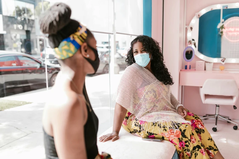 a woman sitting on a bench wearing a face mask, by Meredith Dillman, trending on pexels, afrofuturism, facing each other, spa, milk bar magazine, behind the scenes photo