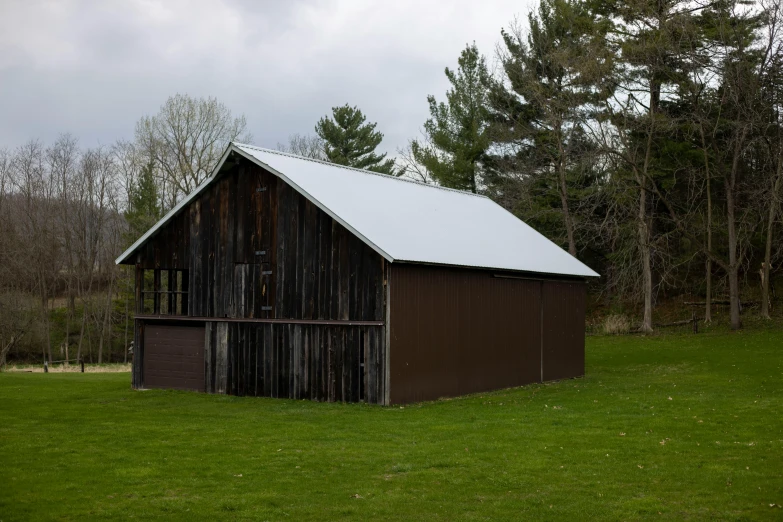 a barn sitting on top of a lush green field, inspired by Gregory Crewdson, unsplash, temporary art, metal cladding wall, brown, museum quality photo, gray