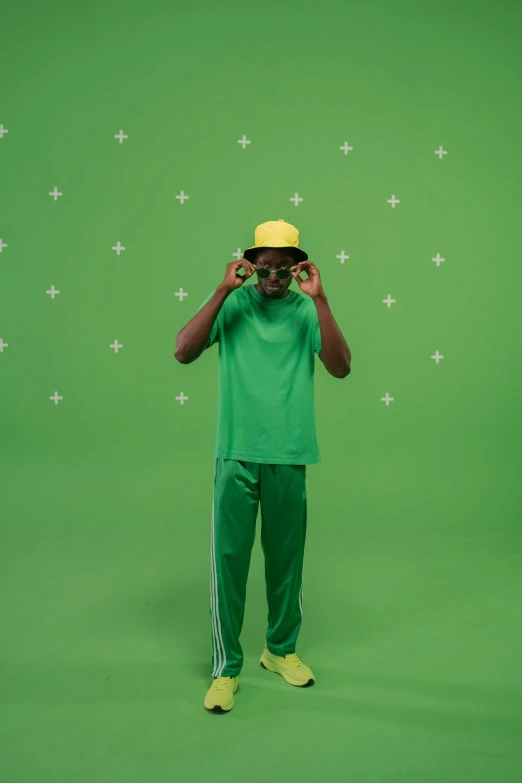 a man standing in front of a green screen, yellow cap, wearing adidas clothing, sussy baka, green legs