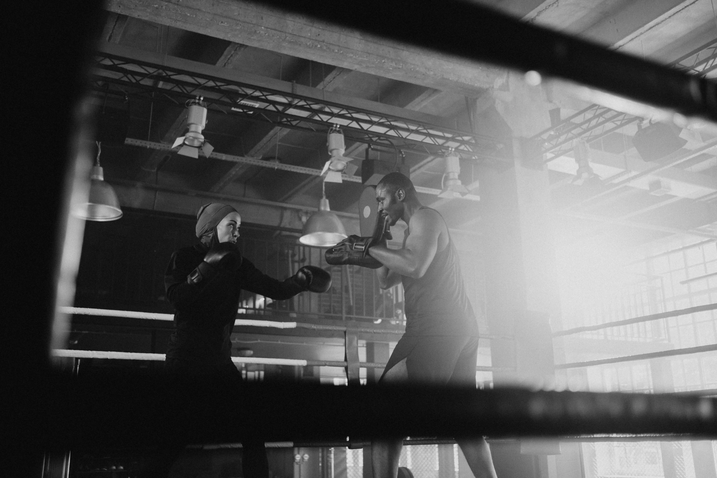 a couple of men standing next to each other in a boxing ring, a black and white photo, by Emma Andijewska, pexels contest winner, performing a music video, working out, woman in a dark factory, in an action pose