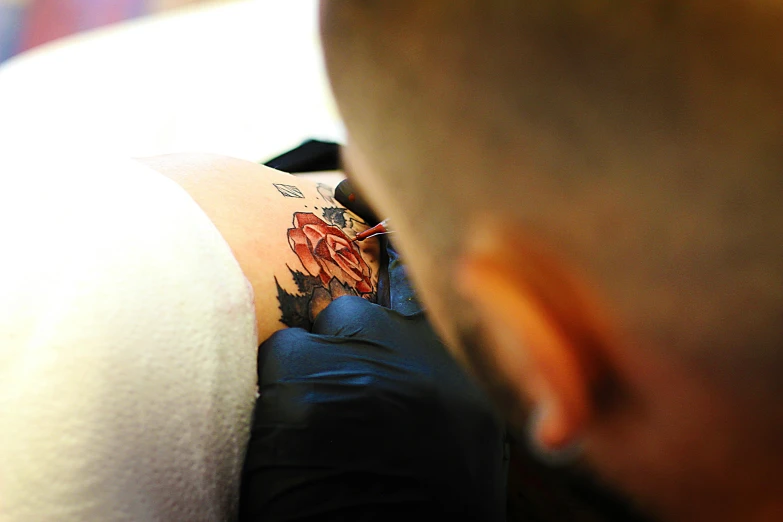 a man getting a tattoo on his arm, a tattoo, by Adam Marczyński, pexels contest winner, blue and red tattoo, backfacing, rose tattoo, 2717433015