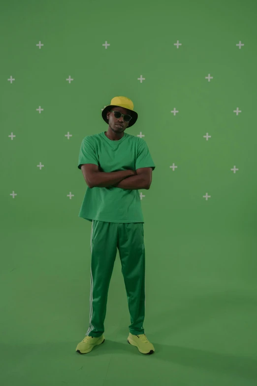 a man standing in front of a green screen, bucket hat, green corduroy pants, wearing adidas clothing, vfx shot