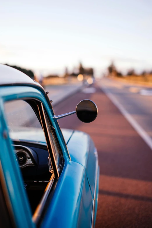 a blue car parked on the side of the road, by Lee Loughridge, unsplash, square, looking back at the camera, 15081959 21121991 01012000 4k, 1 9 7 0 s car window closeup