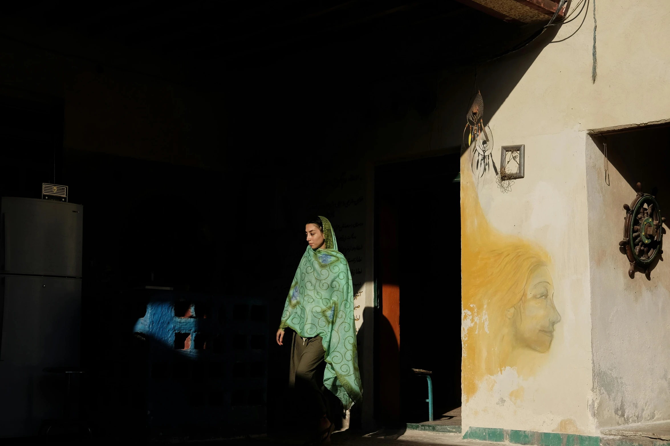 a woman in a green shawl walking down a street, a painting, by Maryam Hashemi, pexels contest winner, hyperrealism, in front of a garage, contre jour, morocco, ( ( theatrical ) )