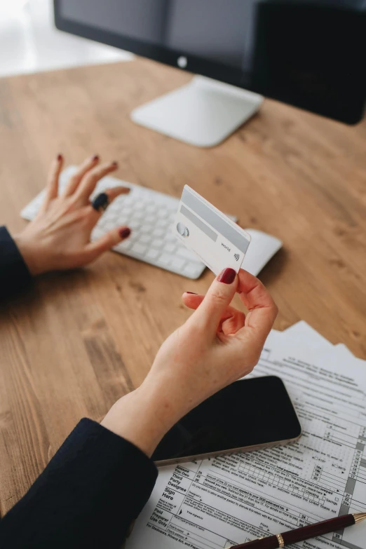 a woman sitting at a desk in front of a computer, by Carey Morris, pexels contest winner, focus on card, garnishment, formulas, kirsi salonen