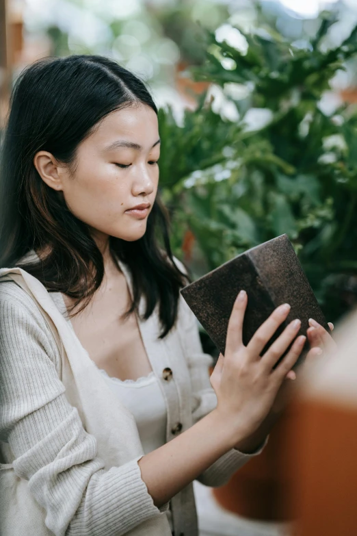 a woman reading a book in a greenhouse, inspired by Ruth Jên, trending on pexels, holding a leather purse, japanese collection product, inspect in inventory image, medium close up portrait