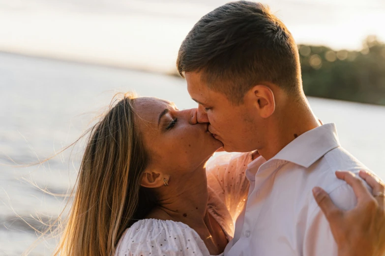 a man and a woman kissing in front of a body of water, pexels contest winner, profile image, golden hour closeup photo, portrait shot 8 k, essence