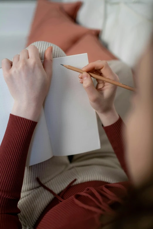 a woman sitting on a couch holding a pencil and paper, a drawing, pexels contest winner, hidden message, soft strokes, instagram post, holding notebook