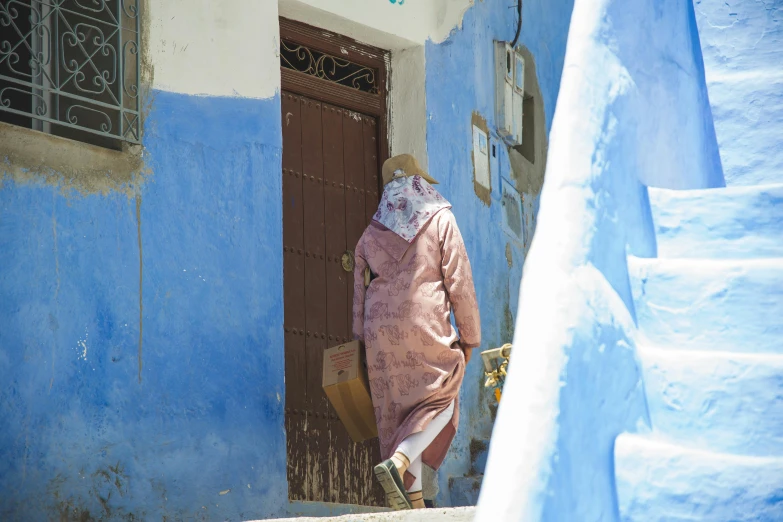 a woman walking up a set of stairs, les nabis, blue colored traditional wear, baggy clothing and hat, view from the streets, thumbnail