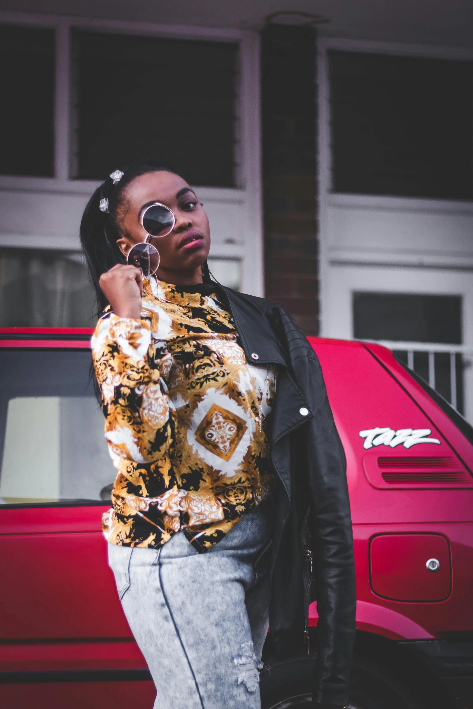 a woman standing in front of a red car talking on a cell phone, an album cover, trending on pexels, patterned clothing, ghetto, headshot profile picture, cropped shirt with jacket