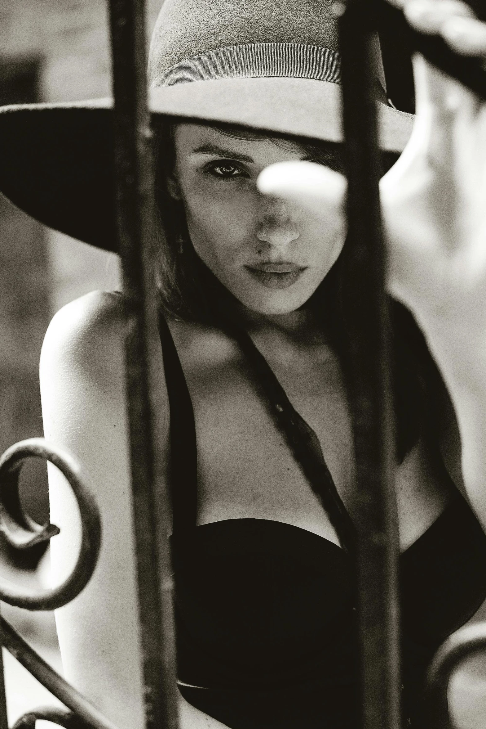 a black and white photo of a woman wearing a hat, a black and white photo, inspired by Helmut Newton, unsplash, standing astride a gate, scarlett johanson, closeup portrait shot, brunette woman