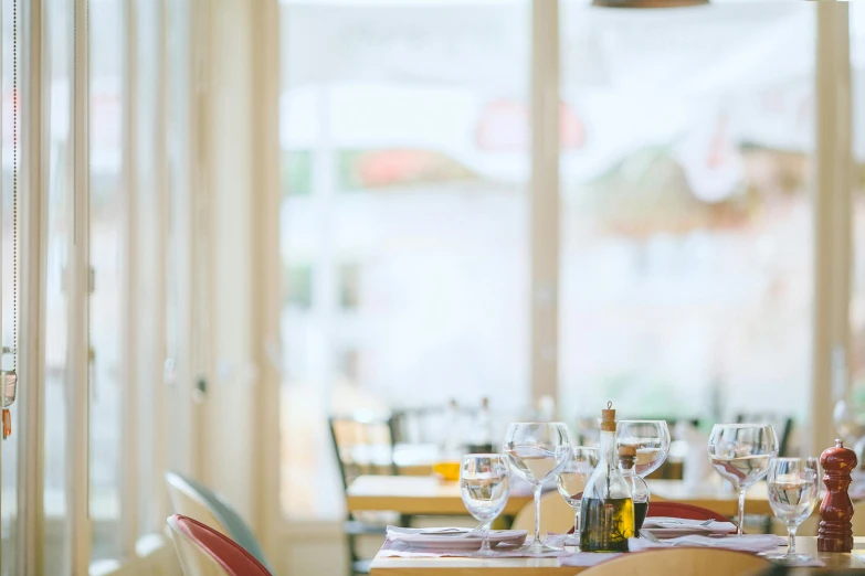 a table that has a bunch of wine glasses on it, unsplash, inside a french cafe, seaside, fan favorite, bright daylight indoor photo