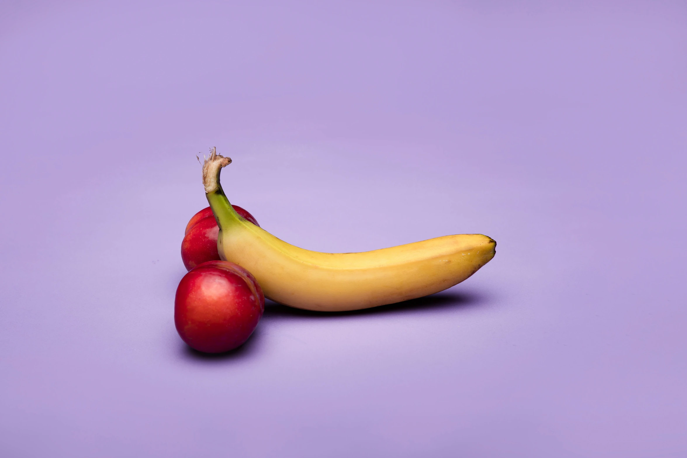 a banana and two cherries on a purple background, inspired by Sarah Lucas, unsplash, sensual bodies, 'untitled 9 ', contracept, photographed for reuters