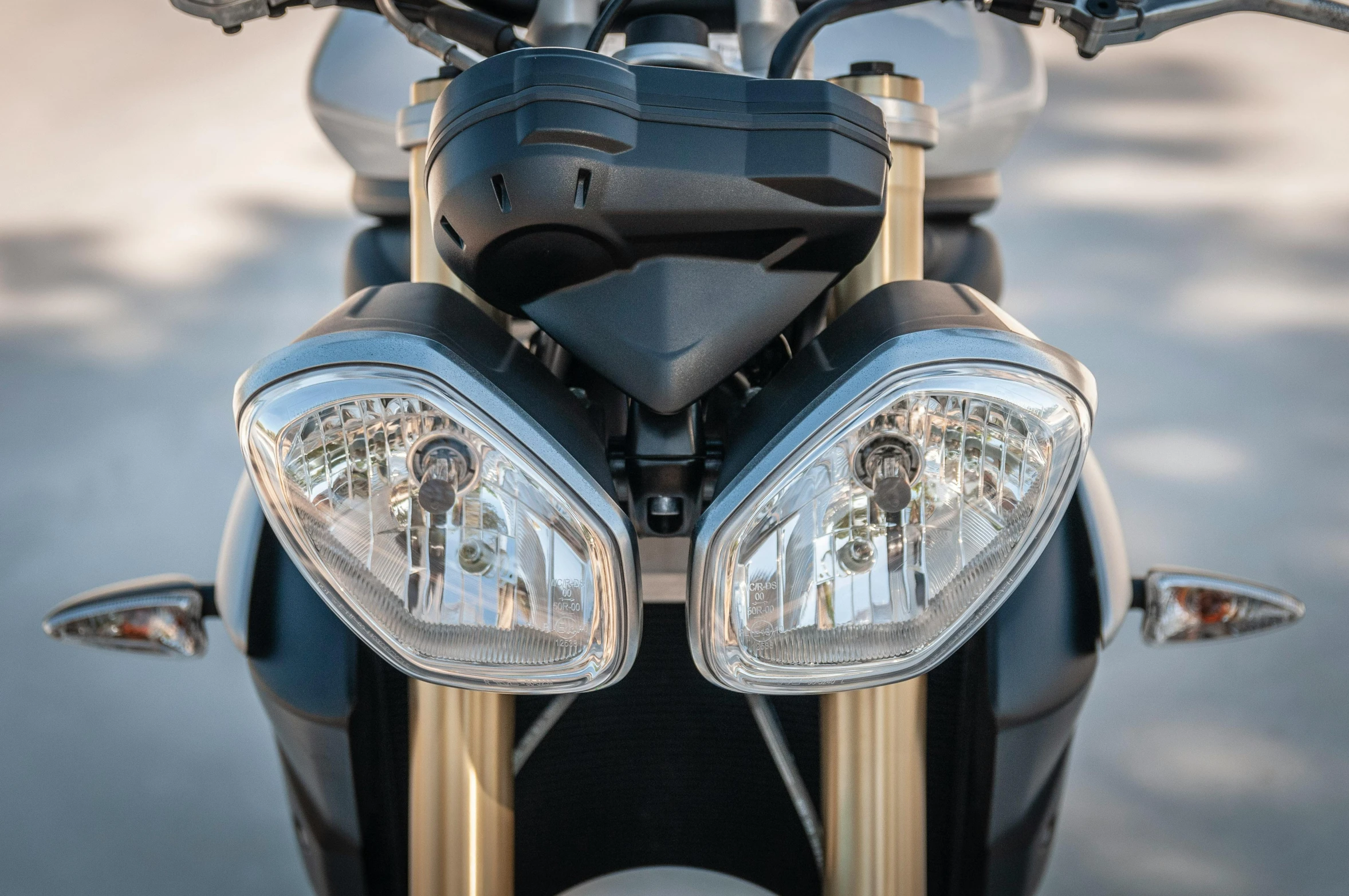 a close up of the headlight of a motorcycle, a picture, by David Simpson, trending on pexels, photorealism, black and gold wires, a pair of ribbed, symmetric lights, triumph