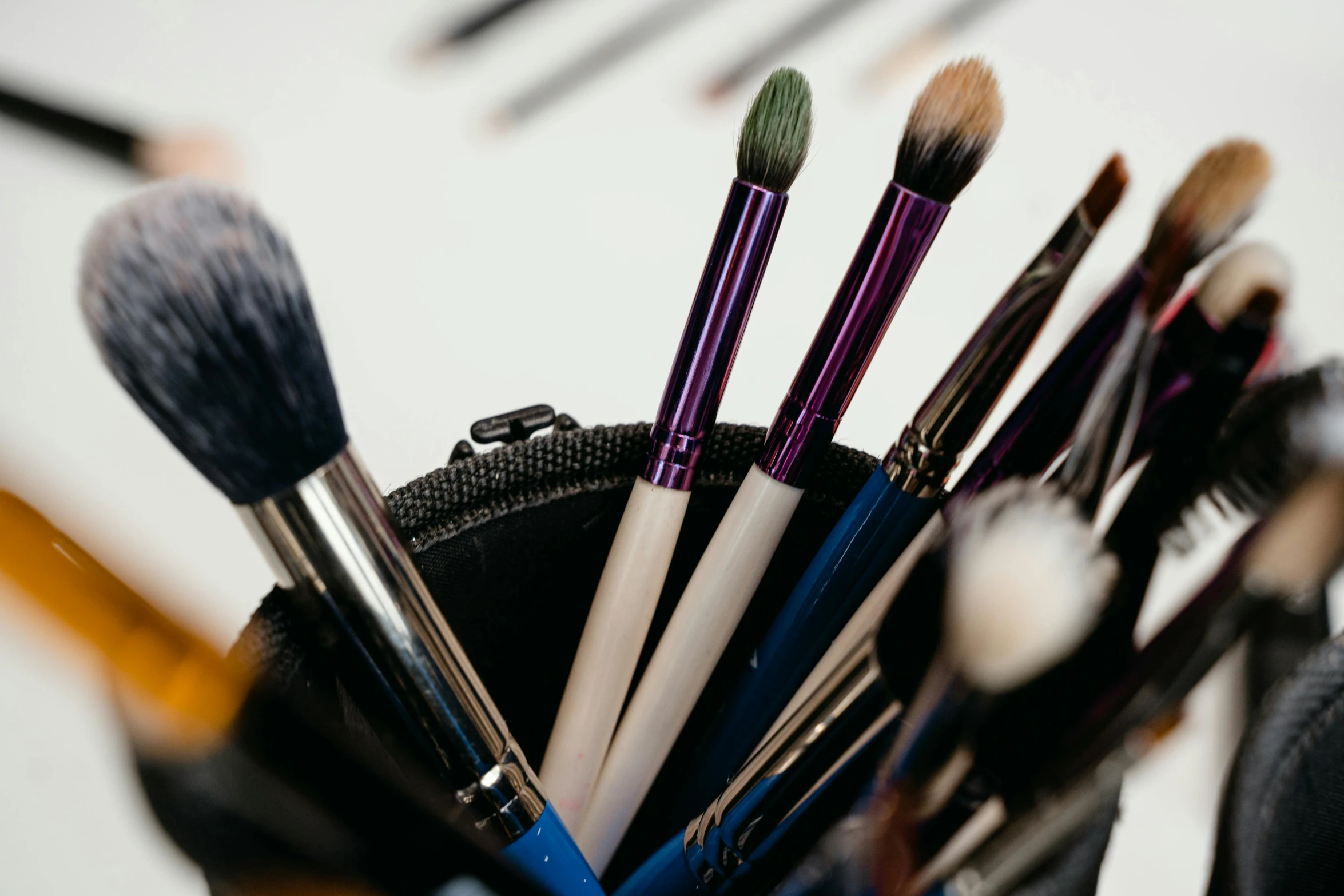 a cup full of makeup brushes sitting on top of a table, by Nicolette Macnamara, trending on pexels, bags under eyes, close up. macro. hyper realistic, complimentary eyeliner, an artistic pose