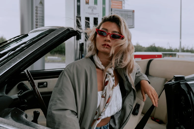 a woman sitting in the driver's seat of a car, trending on pexels, 9 0 - s fashion, gas station, amy sol in the style of, bella poarch