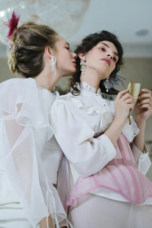 a couple of women standing next to each other, by Penelope Beaton, trending on pexels, rococo, wearing white silk, kissing, valentin serov style, huge earrings and queer make up