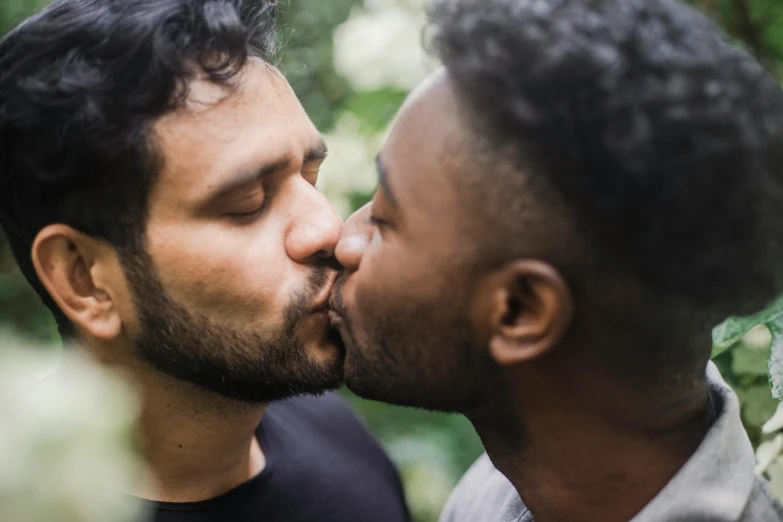 a couple of men standing next to each other, pexels contest winner, romanticism, kiss mouth to mouth, varying ethnicities, curly black beard, press shot