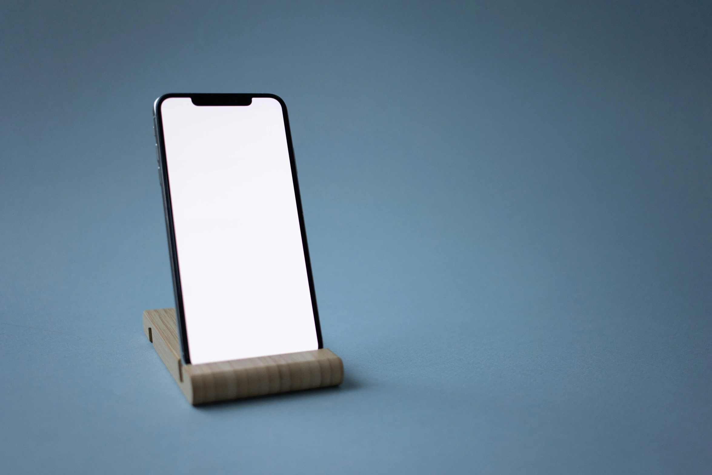 a smartphone sitting on top of a wooden stand, by Carey Morris, minimalism, pale blue backlight, square face, modern minimalist f 2 0, medium long shot