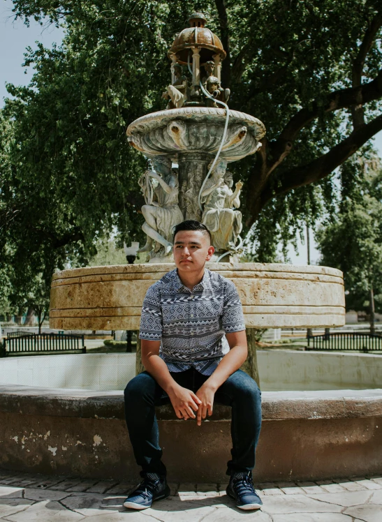 a man sitting in front of a fountain, an album cover, inspired by Eddie Mendoza, he is about 20 years old | short, albuquerque, profile image, single subject