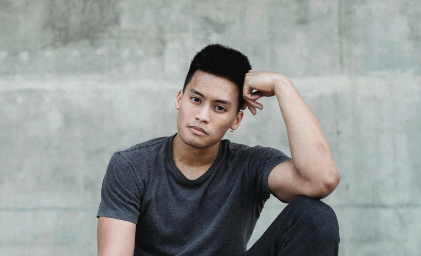 a young man sitting on top of a skateboard, inspired by Byron Galvez, pexels contest winner, realism, chiseled jawline, in front of white back drop, half asian, prideful look