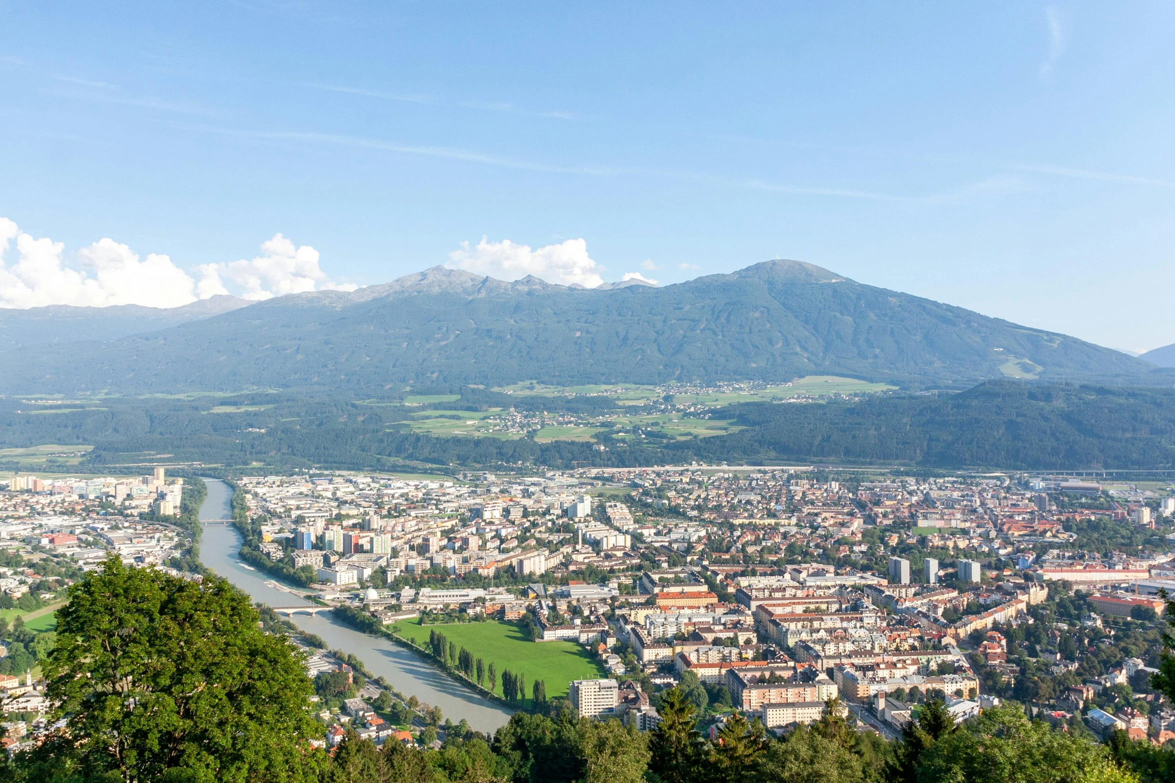 a view of a city with mountains in the background, by Otto Meyer-Amden, pexels contest winner, happening, green valley below, panoramic, high quality product image”