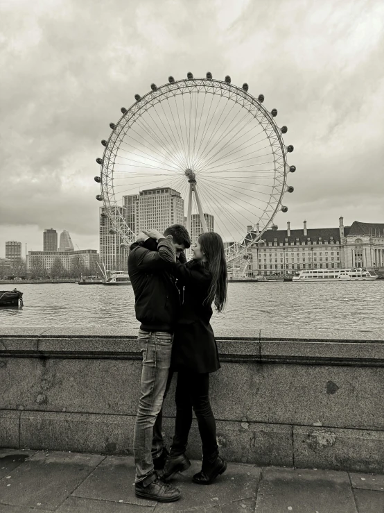 a black and white photo of a couple kissing in front of a ferris wheel, by Sven Erixson, pexels contest winner, london eye, smartphone photo, eyelevel!!! view!!! photography, 8 k -