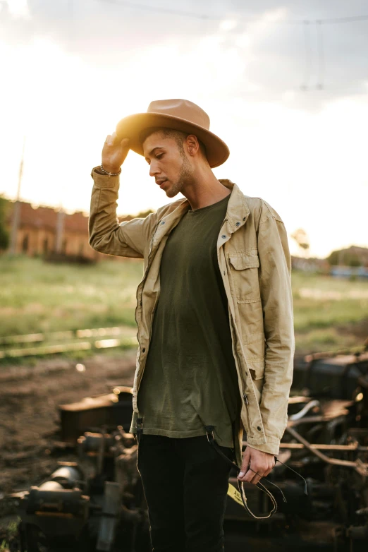 a man standing next to a pile of junk, trending on pexels, renaissance, straw hat and overcoat, wearing green jacket, photo of a model, australian