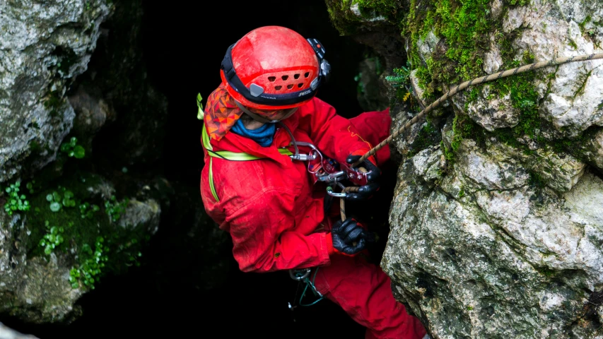 a man in a red suit climbing up a rock, cascade helmet, 9 9 9 9 inside of a dark cave, overhead shot, wearing adventuring gear