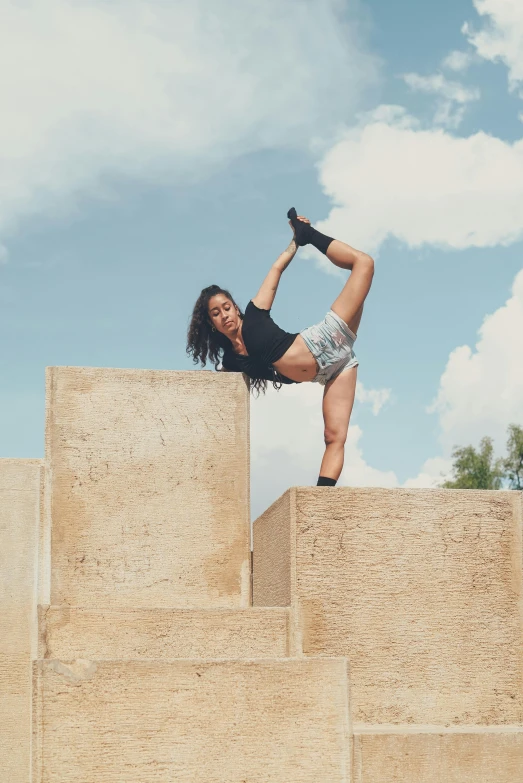 a woman standing on top of a set of stairs, inspired by Elizabeth Polunin, pexels contest winner, arabesque, cinder blocks, isabela moner, cropped red yoga short, having a good time