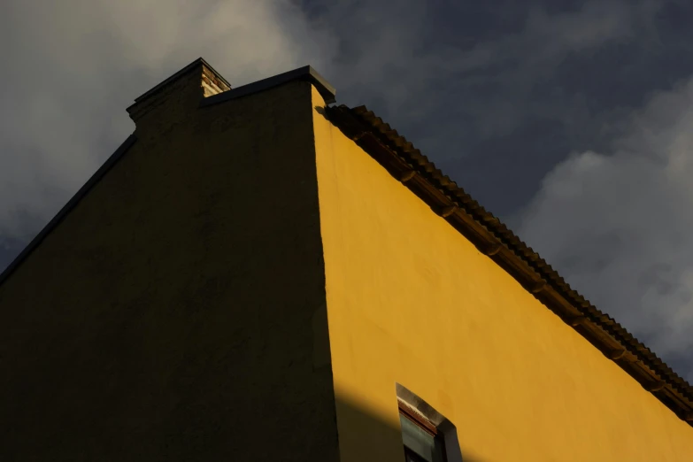 a yellow building with a clock on top of it, a picture, inspired by Orazio Gentileschi, unsplash contest winner, sunset lighting ominous shadows, ignant, minimalist photorealist, hiding in the rooftops