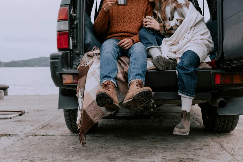 a man and a woman sitting in the back of a truck, trending on pexels, brown boots, picnic, chilly, 1 2 9 7