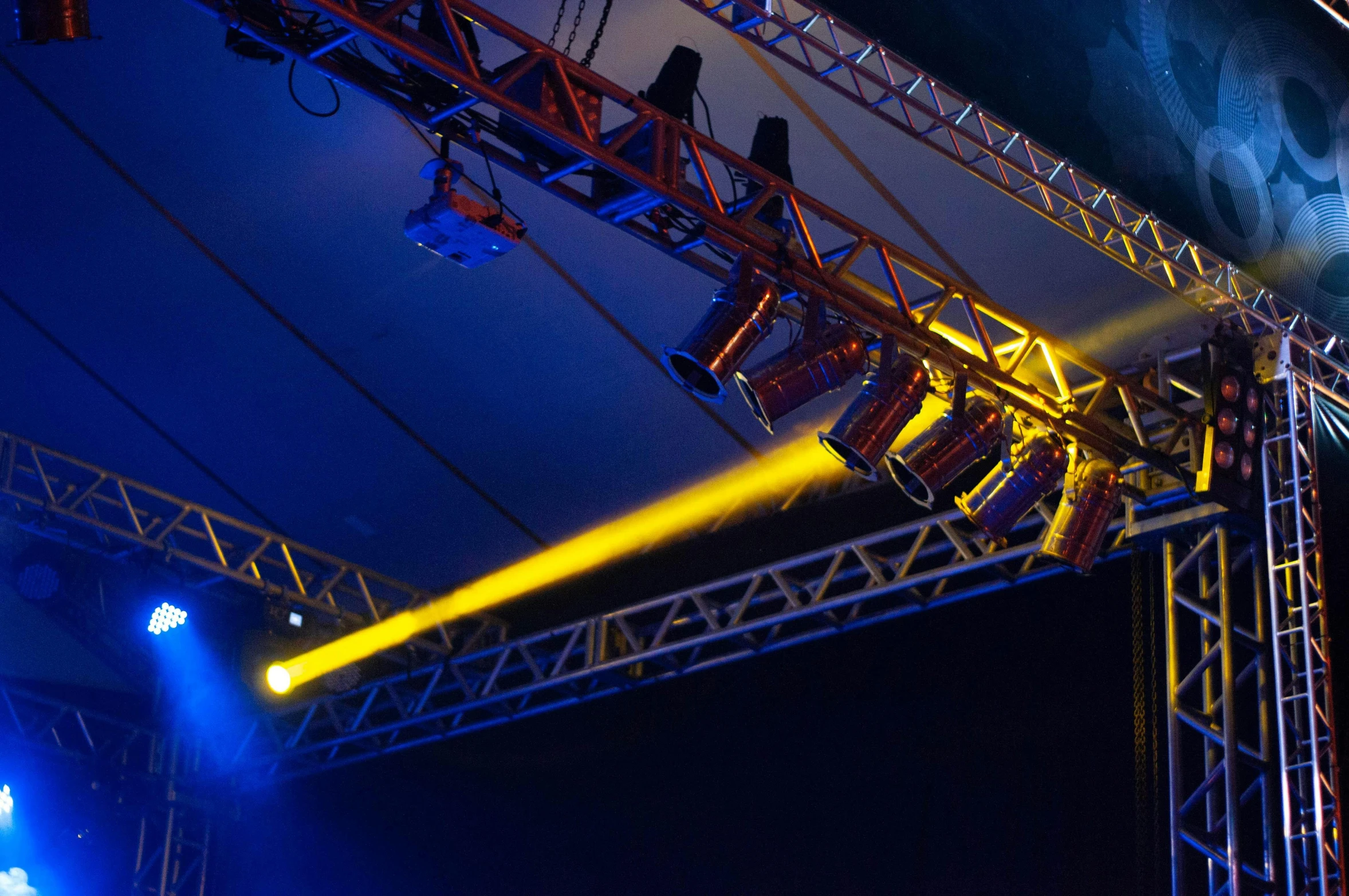 a group of people standing on top of a stage, blue and yellow lighting, hanging cables, hq lighting, construction