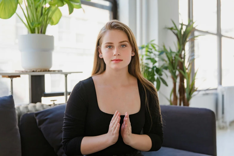 a woman sitting on a couch in a living room, unsplash, anjali mudra, centered shoulders up view, sitting in office, britt marling style 3/4