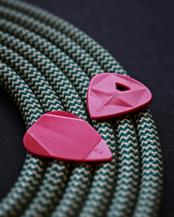 a close up of a close up of a cable, viridian and venetian red, guitar shape build, pink body harness, pieces