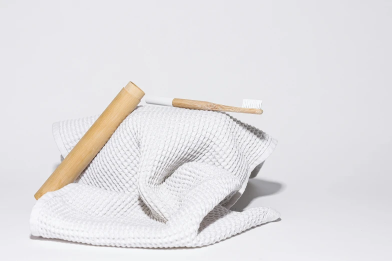 a pair of gloves sitting on top of a towel, inspired by Peter de Sève, unsplash, minimalism, brushes her teeth, made of bamboo, white finish, set against a white background