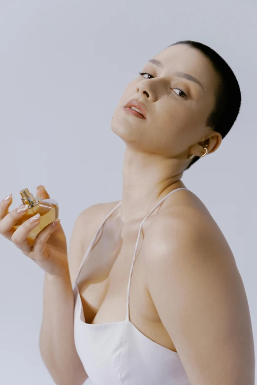 a woman in a white dress holding a bottle of perfume, wearing nothing, woman with black hair, tan complexion, shot with sony alpha