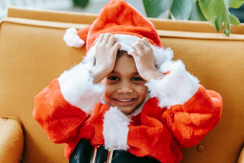 a little boy in a santa suit sitting on a chair, pexels, orange robe, diverse, instagram post, close up character