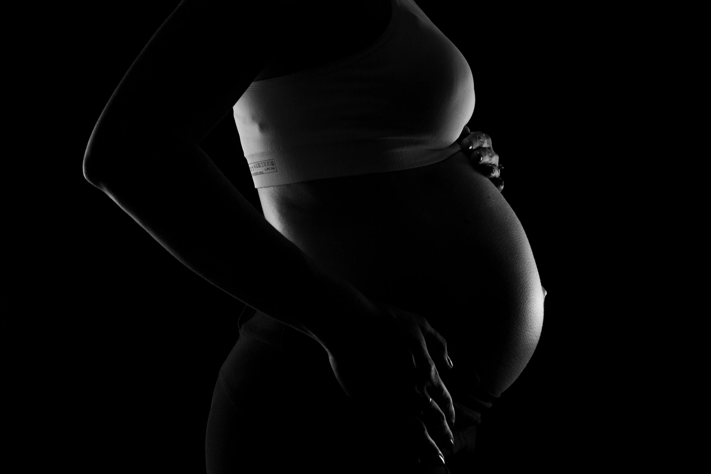 a black and white photo of a pregnant woman, by John Hutton, pixabay, figuration libre, black background!!!!!, fat belly, photo of a black woman, family photo