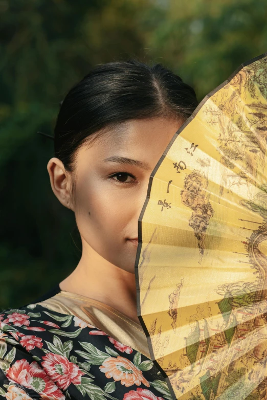 a close up of a person holding a fan, an album cover, inspired by Xu Xi, pexels contest winner, standing with a parasol, japanese facial features, brown, illuminating the area