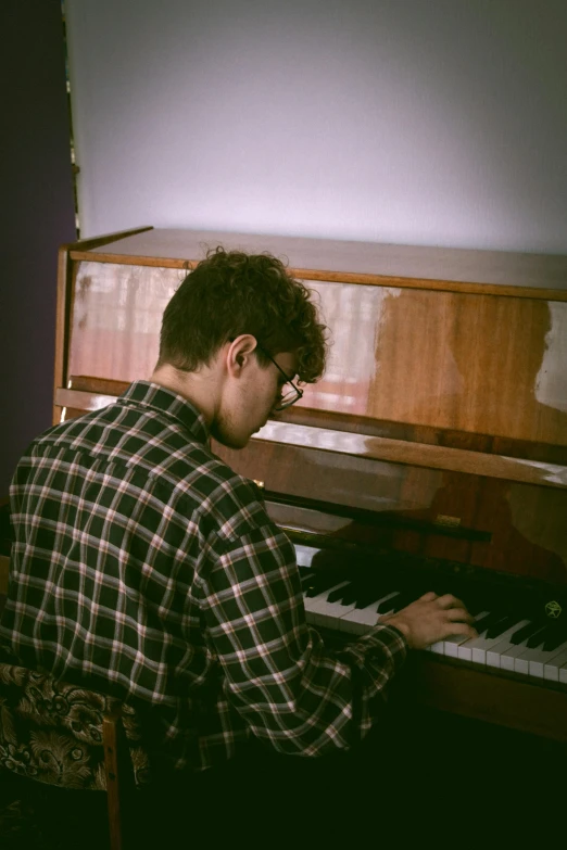 a man sitting at a piano in a room, an album cover, by Jacob Toorenvliet, unsplash, young handsome pale roma, low quality grainy, low fi, performing