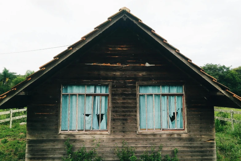 an old wooden house with two blue windows, a photo, unsplash, background image, 1980s photo, makeshift houses, extremely scary