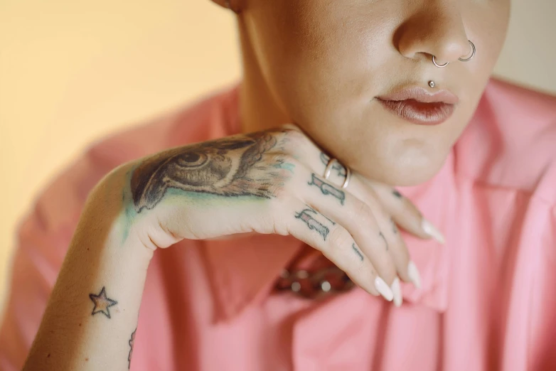 a close up of a person with tattoos on their hands, inspired by Elsa Bleda, trending on pexels, hyperrealism, smooth pink skin, portrait androgynous girl, with a pointed chin, plain background