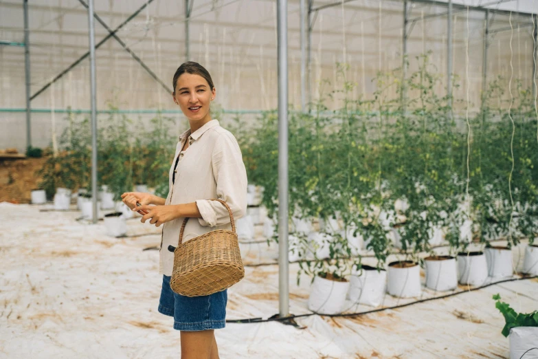 a woman standing in a greenhouse holding a basket, pexels contest winner, wearing a linen shirt, demna gvasalia, in avila pinewood, hydroponic farms