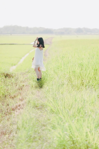 a woman in a white dress standing in a field, by Tan Ting-pho, side portrait of a girl walking, medium format, rice, overexposed photograph