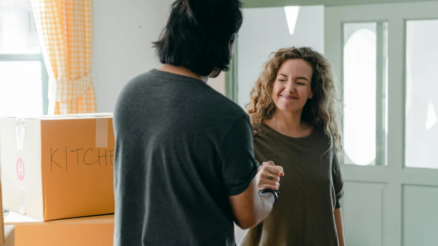 a woman standing next to a man in a room, by Lee Loughridge, pexels contest winner, smiling playfully, selling insurance, manuka, moving