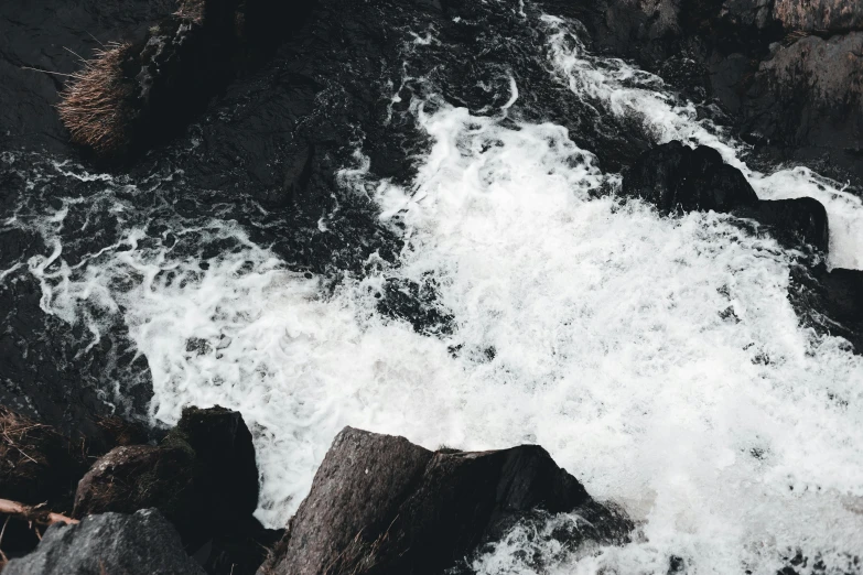 a man riding a surfboard on top of a wave, pexels contest winner, process art, with lots of dark grey rocks, white and black color palette, river rapids, thumbnail