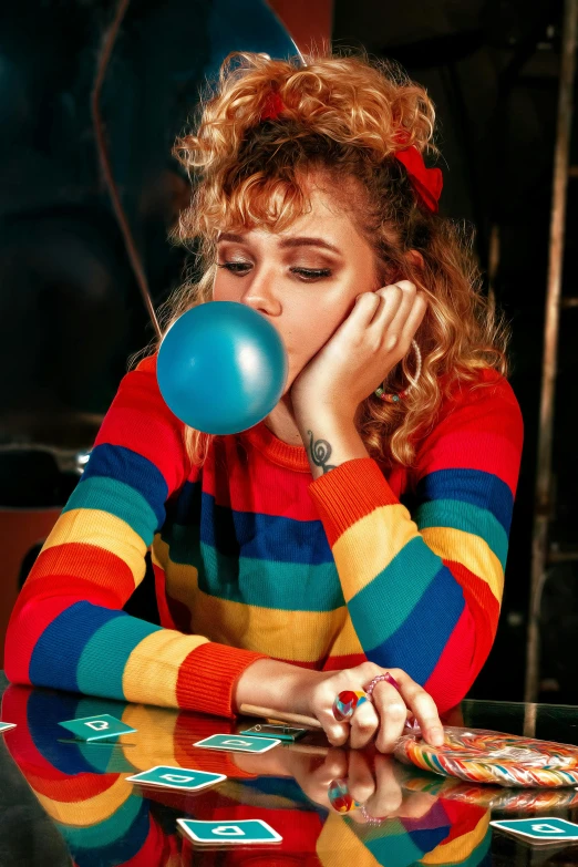 a woman blowing a bubble while sitting at a table, an album cover, inspired by Elsa Bleda, trending on pexels, pop art, rainbow clothes, stripes, gumball machine, chalk