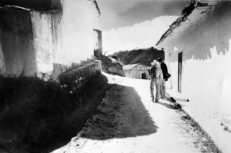 a black and white photo of a person on a skateboard, a black and white photo, by Samuel Birmann, dada, in a village street, neo - andean architecture, two men, white houses